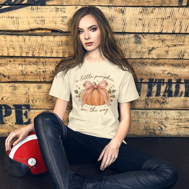 Woman wearing a cream fall maternity tee with a pumpkin on the way design